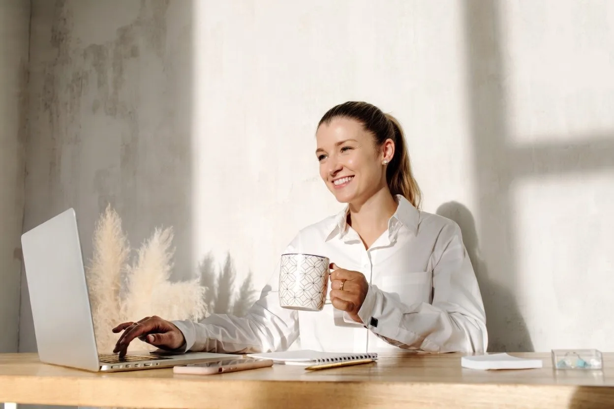 Lauren working at her desk with a laptop and a mug in natural light